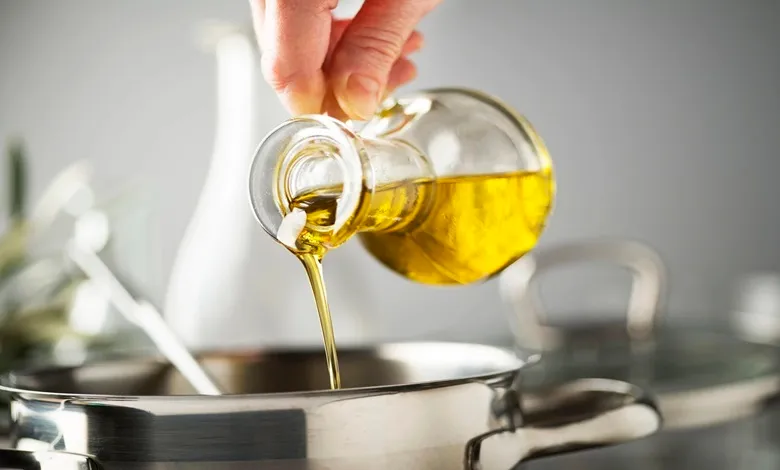 فردی در حال ریختن روغن مایع در ماهیتابه به منظور پخت غذا است.