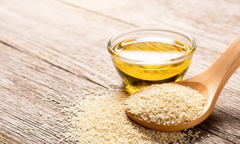 عکس روغن کنجد در کاسه و یک قاشق دانه کنجد