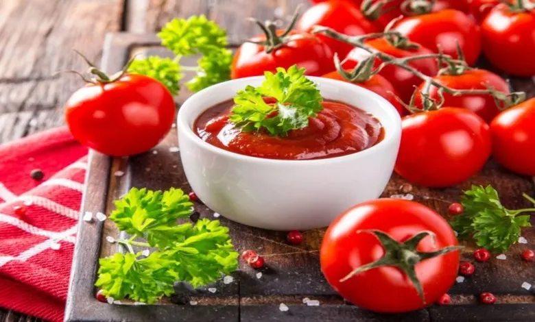 عکس از رب گوجه و تعدادی گوجه فرنگی که بر روی سینی قرار دارند.